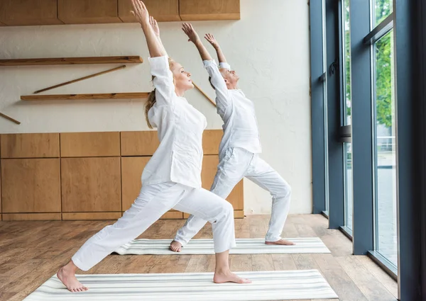 Descalço sporty casal sênior praticando ioga em casa — Fotografia de Stock