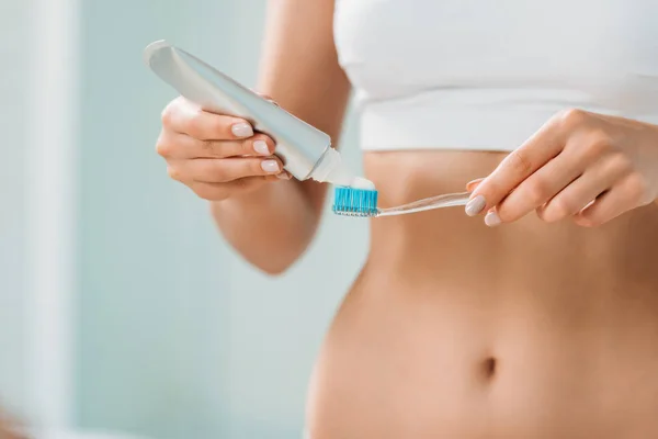 Cropped shot of young woman in underwear holding toothbrush and toothpaste in bathroom — Stock Photo