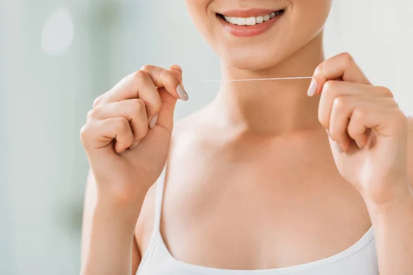 Cropped shot of smiling young woman holding dental floss — Stock Photo