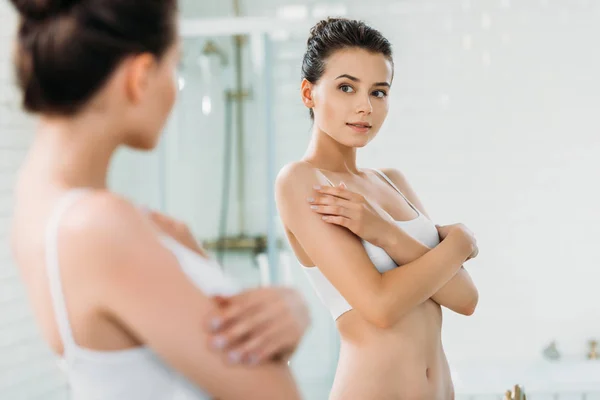 Bella giovane donna bruna in biancheria intima guardando specchio in bagno — Foto stock