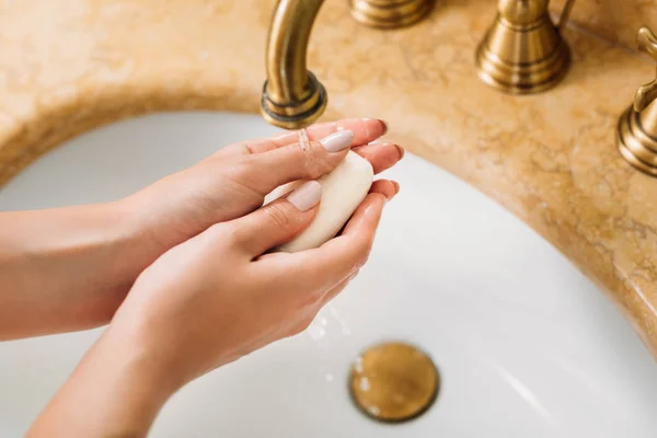 Tiro recortado de la mujer lavándose las manos con jabón en el baño - foto de stock