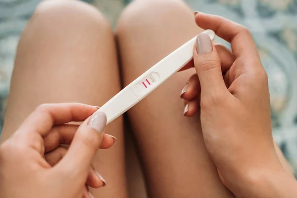 Inyección recortada de mujer joven sosteniendo la prueba de embarazo - foto de stock