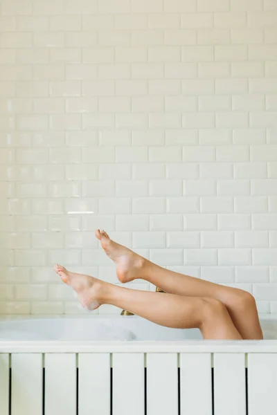 Section basse de la jeune femme se détendre dans la baignoire avec de la mousse — Photo de stock