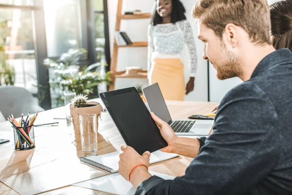 Visão lateral do empresário segurando tablet com tela em branco durante reunião de negócios com colegas — Fotografia de Stock