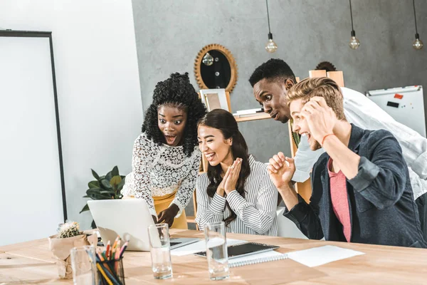 Uomini d'affari multiculturali eccitati che guardano insieme lo schermo del computer portatile sul posto di lavoro in ufficio — Foto stock