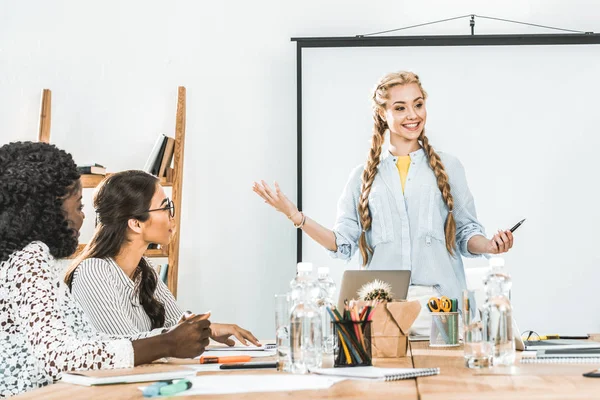 Smiling businesswoman presenting new information to multicultural colleagues at business meeting — Stock Photo
