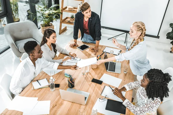 Businesswoman giving documents to african american businessman during meeting in office — Stock Photo