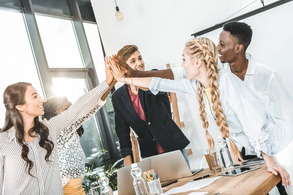 Multicultural young business team holding hands together in office — Stock Photo