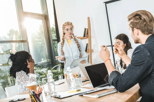 Grupo multicultural de empresarios que discuten el trabajo mientras están sentados en el lugar de trabajo en la oficina - foto de stock