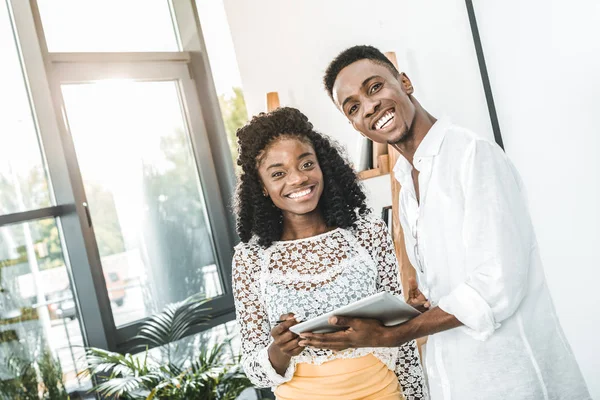 Retrato de sorridentes empresários afro-americanos com tablet nas mãos olhando para a câmera — Fotografia de Stock