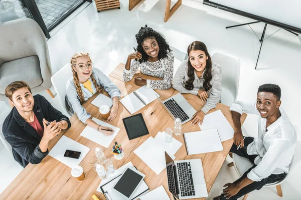 High angle view of young business team looking at camera during business conference in office — Stock Photo