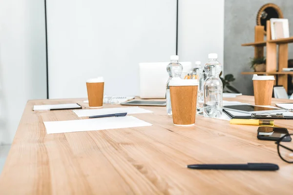 Lieu de travail vide avec gobelets jetables, appareils numériques et papiers au bureau — Photo de stock