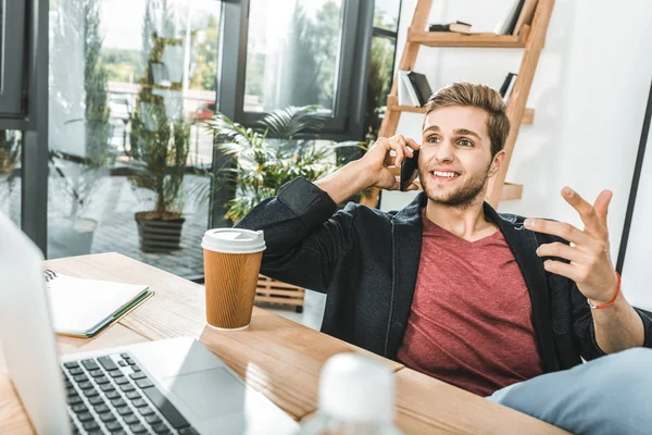 Ritratto di un giovane uomo d'affari che parla su smartphone sul posto di lavoro in ufficio — Foto stock