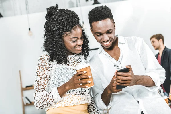 Sorridenti uomini d'affari africani americani che utilizzano smartphone insieme in ufficio — Foto stock