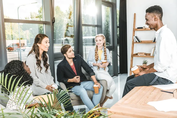 Grupo multiétnico de compañeros de trabajo de negocios teniendo conversación durante el descanso de café en la oficina - foto de stock