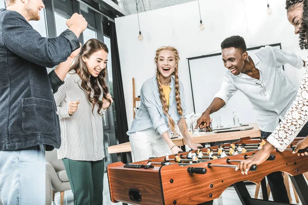 Les gens d'affaires multiculturels célèbrent la victoire tout en jouant au baby-foot ensemble — Photo de stock