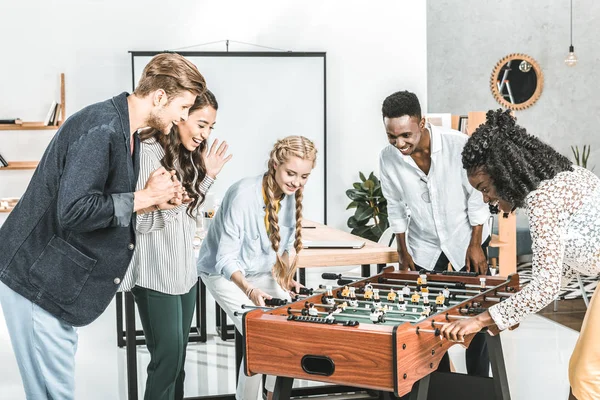 Homens de negócios multiculturais e mulheres de negócios jogando futebol de mesa juntos no escritório — Fotografia de Stock