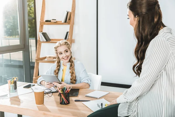 Young multicultural businesswomen having conversation at workplace in office — Stock Photo