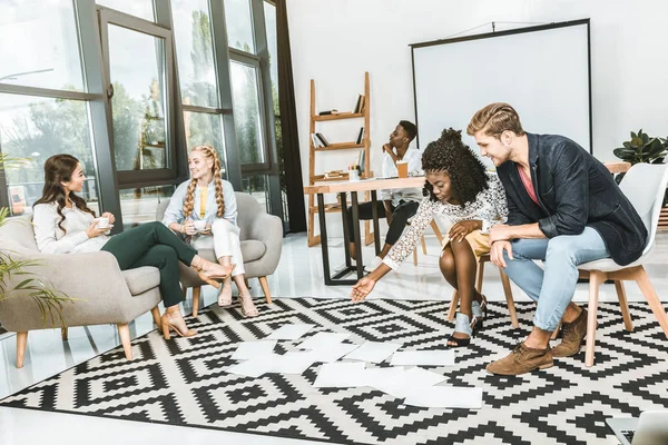 Des gens d'affaires multiculturels regardant des papiers sur le sol ensemble dans le bureau — Photo de stock