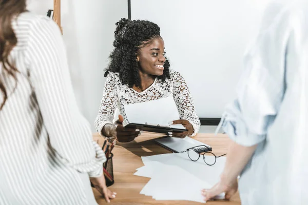 Retrato de la alegre mujer de negocios afroamericana durante la reunión de negocios con colegas en el cargo - foto de stock