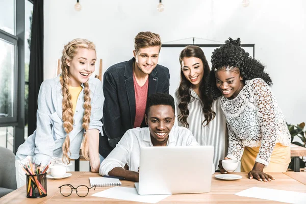 Portrait de jeunes entreprises multiethniques travaillant ensemble sur un ordinateur portable — Photo de stock