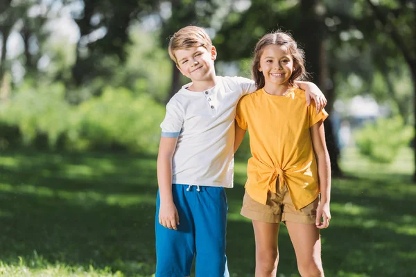 Beautiful happy children embracing and smiling at camera in park — Stock Photo