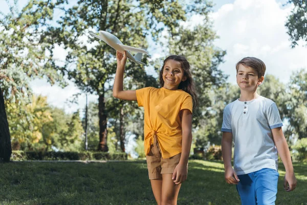 Mignon souriant enfants jouer avec avion modèle dans le parc — Photo de stock