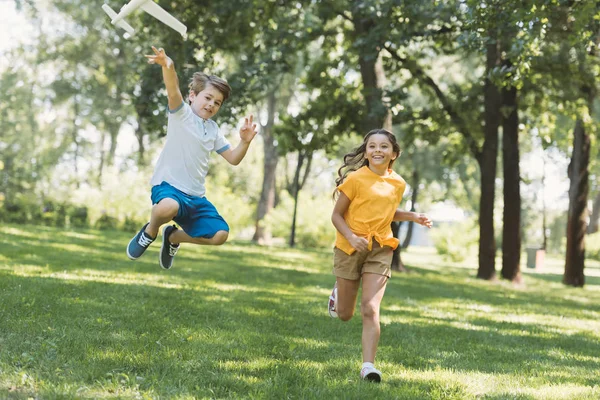 Adorable feliz niños jugando con avión modelo en parque - foto de stock