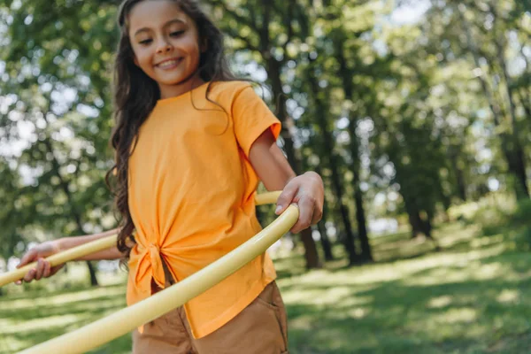 Милый улыбающийся ребенок играет с обручем в парке — стоковое фото