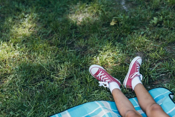 Low section of kid resting on green grass in park — Stock Photo