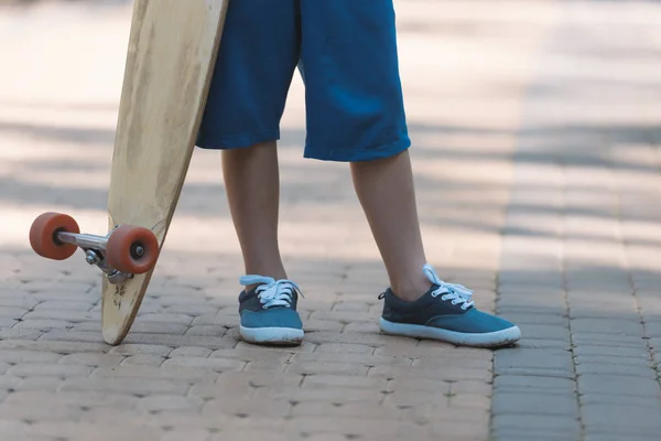 Low section of child holding longboard in park — Stock Photo