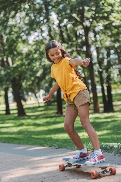 Adorabile bambino felice equitazione skateboard nel parco — Foto stock