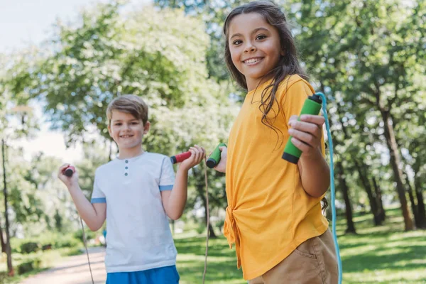 Adorável crianças felizes caminhadas pulando cordas e sorrindo para a câmera no parque — Fotografia de Stock