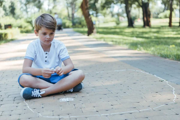 Милий маленький хлопчик малює крейдою в парку — стокове фото