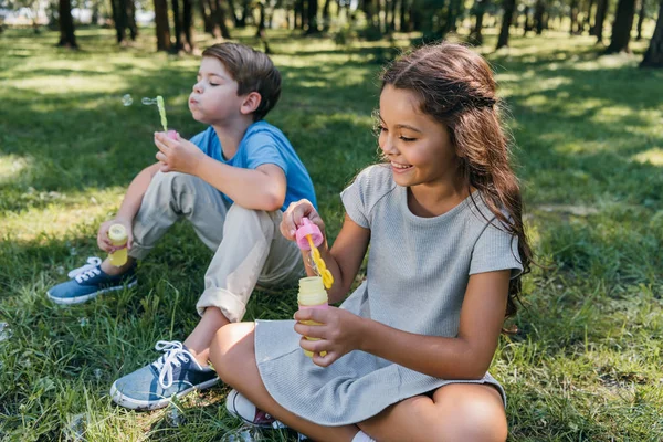 Carino bambini felici soffiando bolle di sapone nel parco — Foto stock