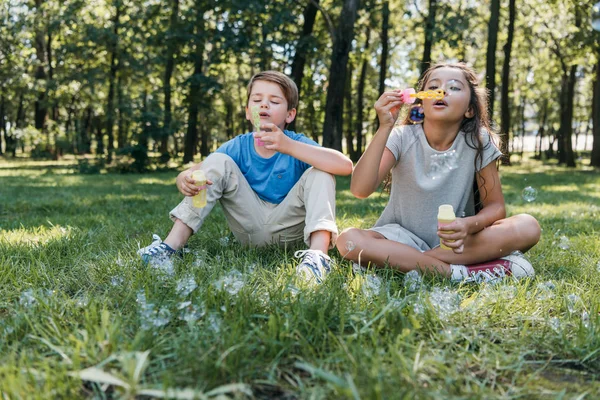 Adorabili bambini che soffiano bolle di sapone nel parco — Foto stock