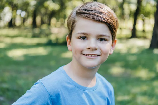 Portrait de heureux petit garçon souriant à la caméra dans le parc — Photo de stock