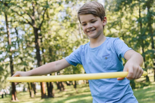 Cute happy child playing with hula hoop in park — Stock Photo