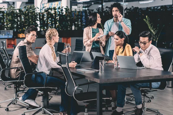 Partenaires d'affaires multiethniques se réunissant à table dans un bureau moderne — Photo de stock