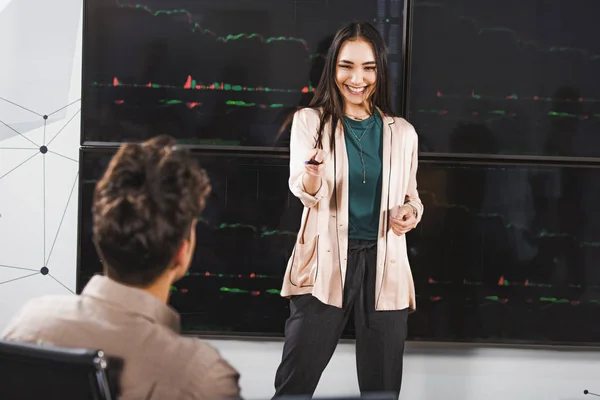 Sorridente donna d'affari asiatica che mostra presentazione e punta sul collega maschile presso l'ufficio moderno — Foto stock