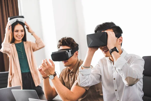 Dos hombres de negocios sonrientes usando auriculares de realidad virtual en la oficina moderna — Stock Photo