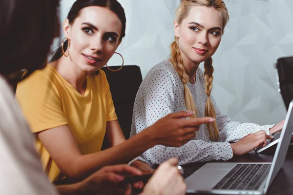 Donna d'affari che punta il dito contro lo schermo del computer portatile al collega in ufficio moderno — Foto stock