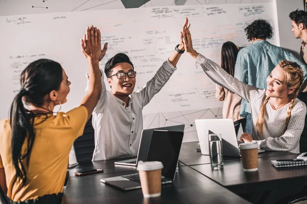 Young asian businessman taking high fives to female colleagues at modern office — Stock Photo