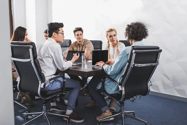 Pessoas de negócios multiétnicos que têm discussão à mesa com laptops no escritório moderno — Fotografia de Stock