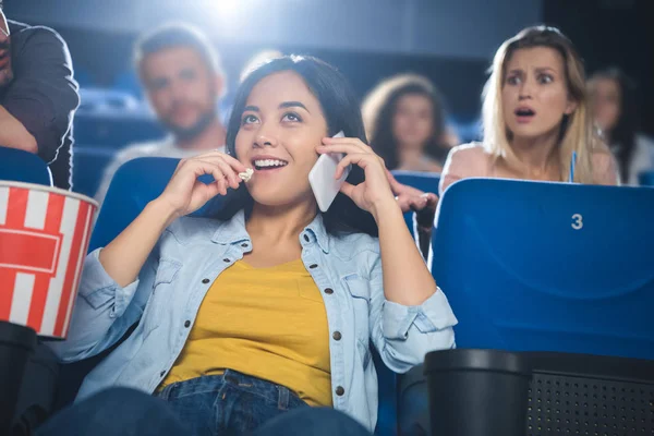 Asiatin spricht auf Smartphone, während sie Film im Kino anschaut — Stockfoto