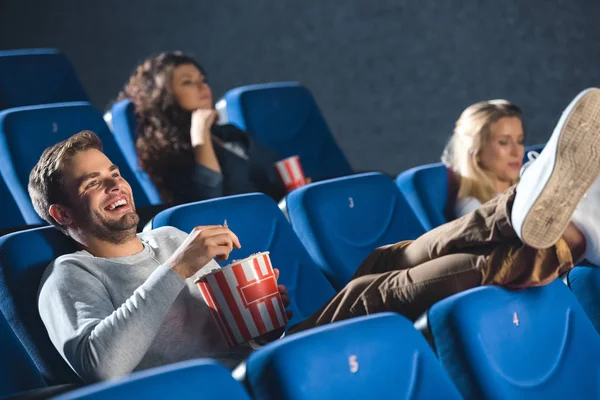 Веселый мужчина со смехом попкорна во время просмотра фильма в кино — стоковое фото