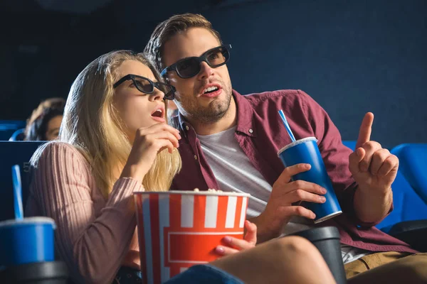 Emotional couple in 3d glasses with popcorn watching film together in cinema — Stock Photo
