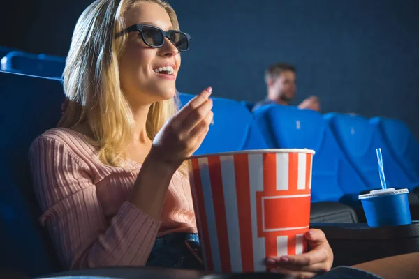 Donna sorridente in occhiali 3d con popcorn guardando film da solo nel cinema — Foto stock