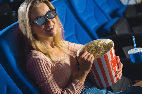 Mujer joven en gafas 3D con palomitas de maíz viendo película solo en el cine - foto de stock