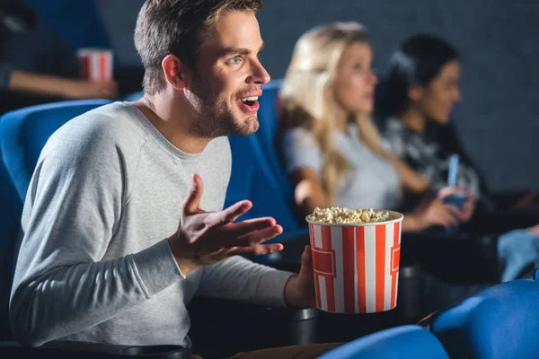 Selective focus of emotional man with popcorn in cinema — Stock Photo